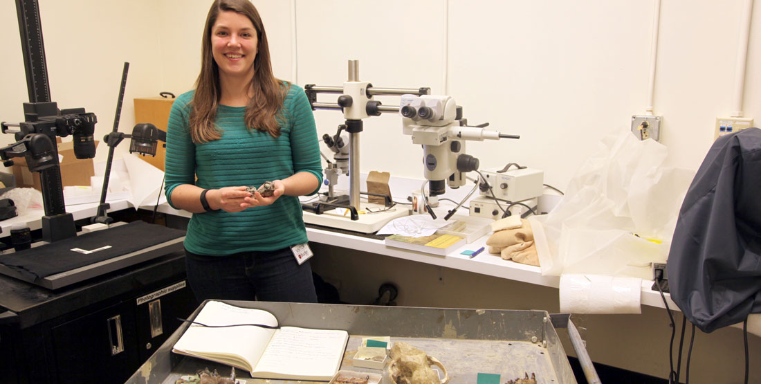 A female researcher stands in a workroom holding a fossil jaw