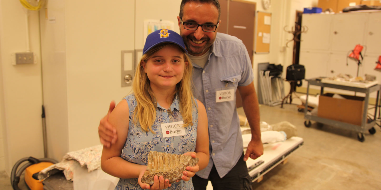 A girl and her father hold a mammoth tooth