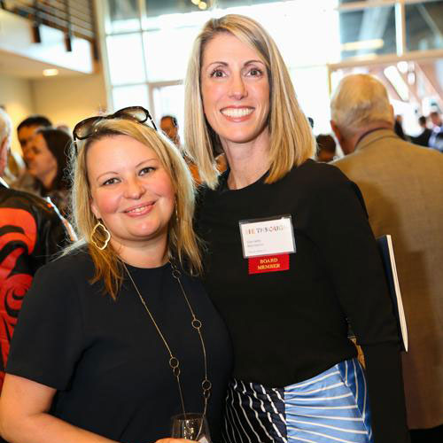 two women pose for a photo at a gala event