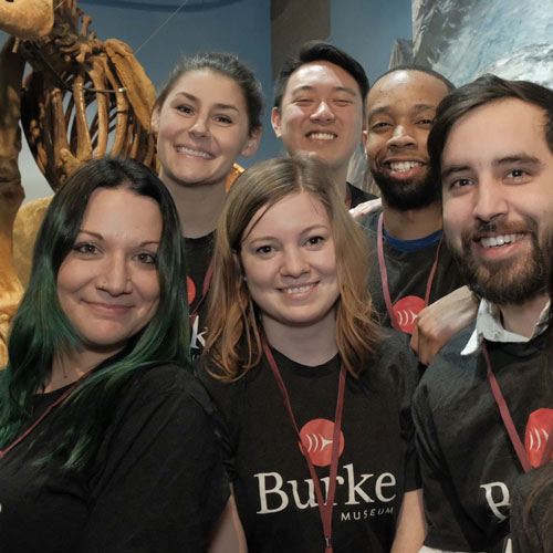 a group of young people pose for a photo in front of a mastodon