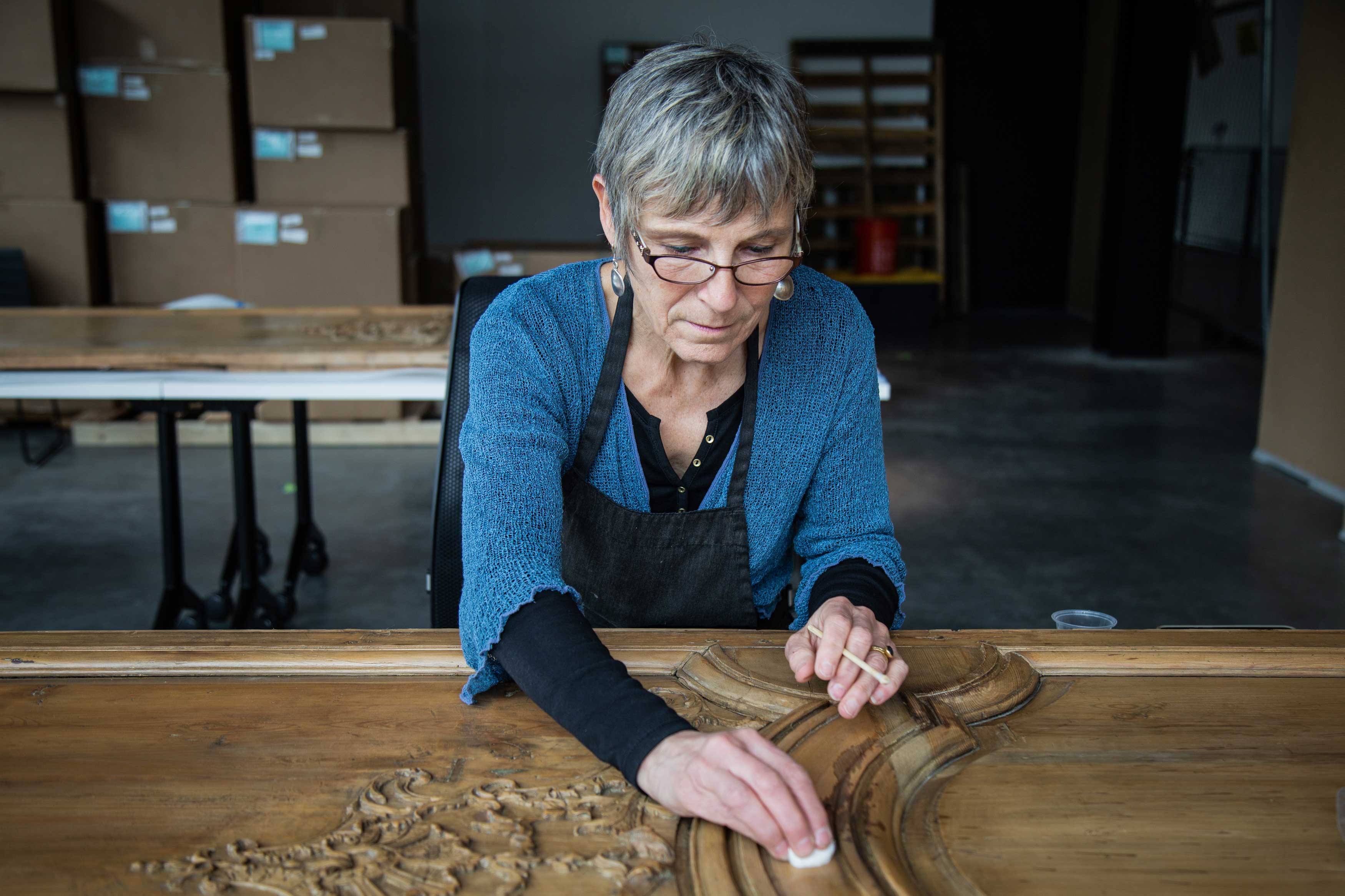 A woman gently cleans the boiserie panel with a cotton ball