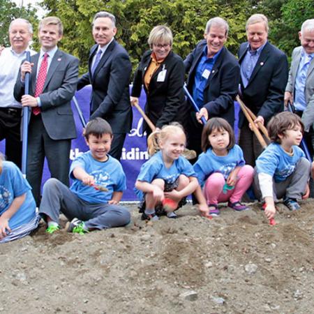 Large multi-age group standing with shovels and hard hats 