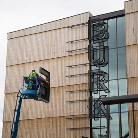 Two crew members use a lift to install the letter E on the new Burke sign