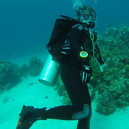 A female scuba diver swimming near a reef