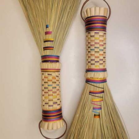 two traditional brooms with intricate woven details on the handles