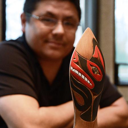 A man sits with a canoe paddle rattle