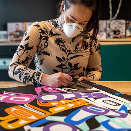 A woman paints a colorful mural