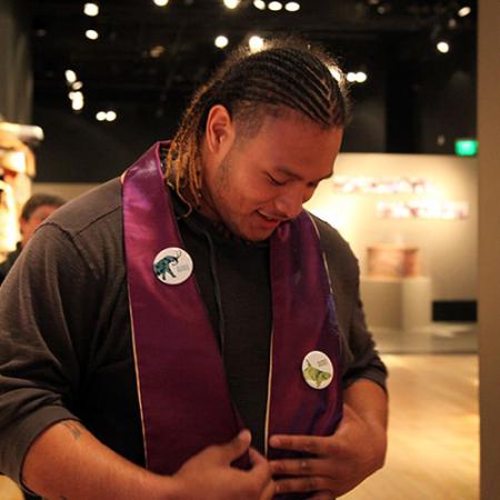 a young man looks down at a stole that was placed over his shoulders