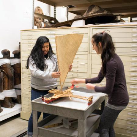 two young women adjust the sail on a model boat