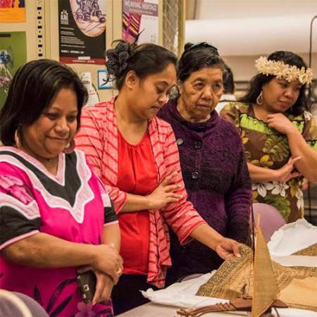 a group of women look at woven items in the Burke Museum collection