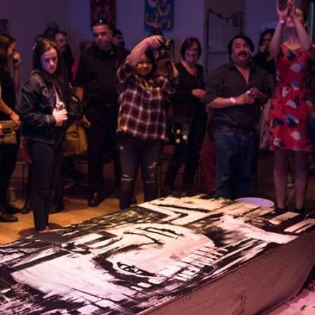 Crowd of people looking at artwork on the ground