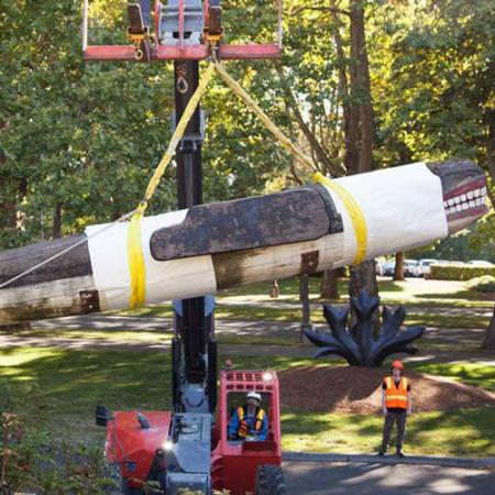 A large whale carving is carefully hoisted by a crane