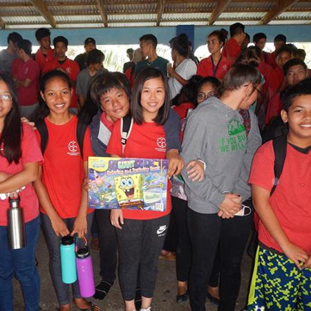 A group of schoolchildren wearing backpacks hold a picture of Spongebob Squarepants