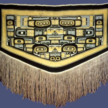 A Chilikat Dancing Blanket decorated with fringe and yellow and black and blue patterns