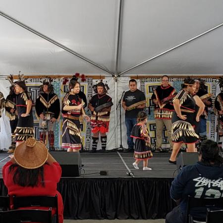 a group of Native dancers on stage in regalia