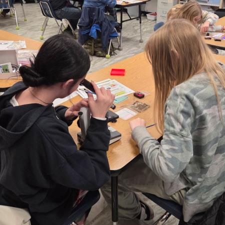 kids in a classroom look through a microscope