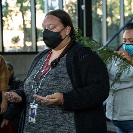 a person stands with arms in front of her during a blessing of the hands ceremony at the burke