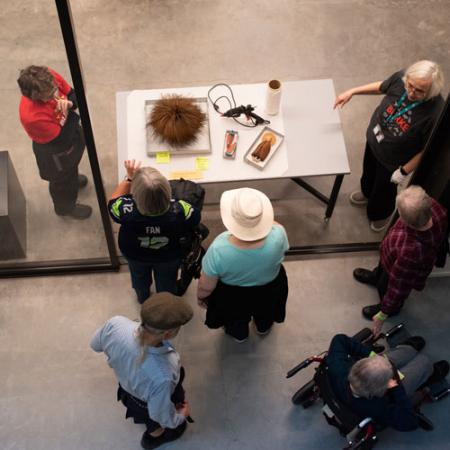 two staff members talk to visitors through an open door with objects out on a table