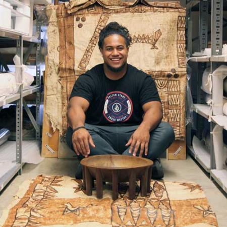 A young man sits with a kava bowl in front of him