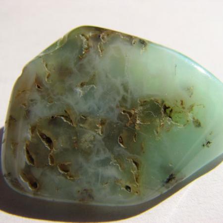 A close up view of a rough emerald with brown spots