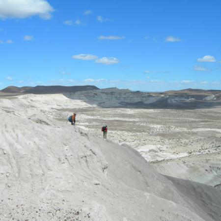 Two people stand in a white sandy desert with blue sky