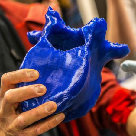 A person holding a blue 3D printed mammoth bone