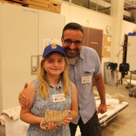 A girl and her father hold a mammoth tooth