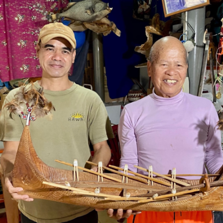 Syaman and father Syapen pose with a model of a Tatala they made.