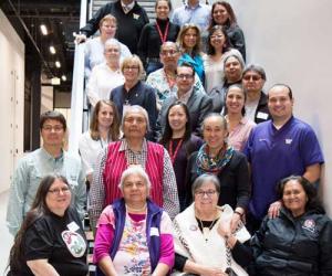 a group photo of the burke's native american advisory board. they are posing on several levels of steps in the burke museum main staircase