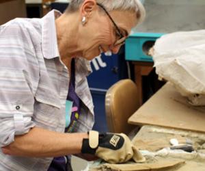 A woman scrapes away sandstone from the T. rex fossil